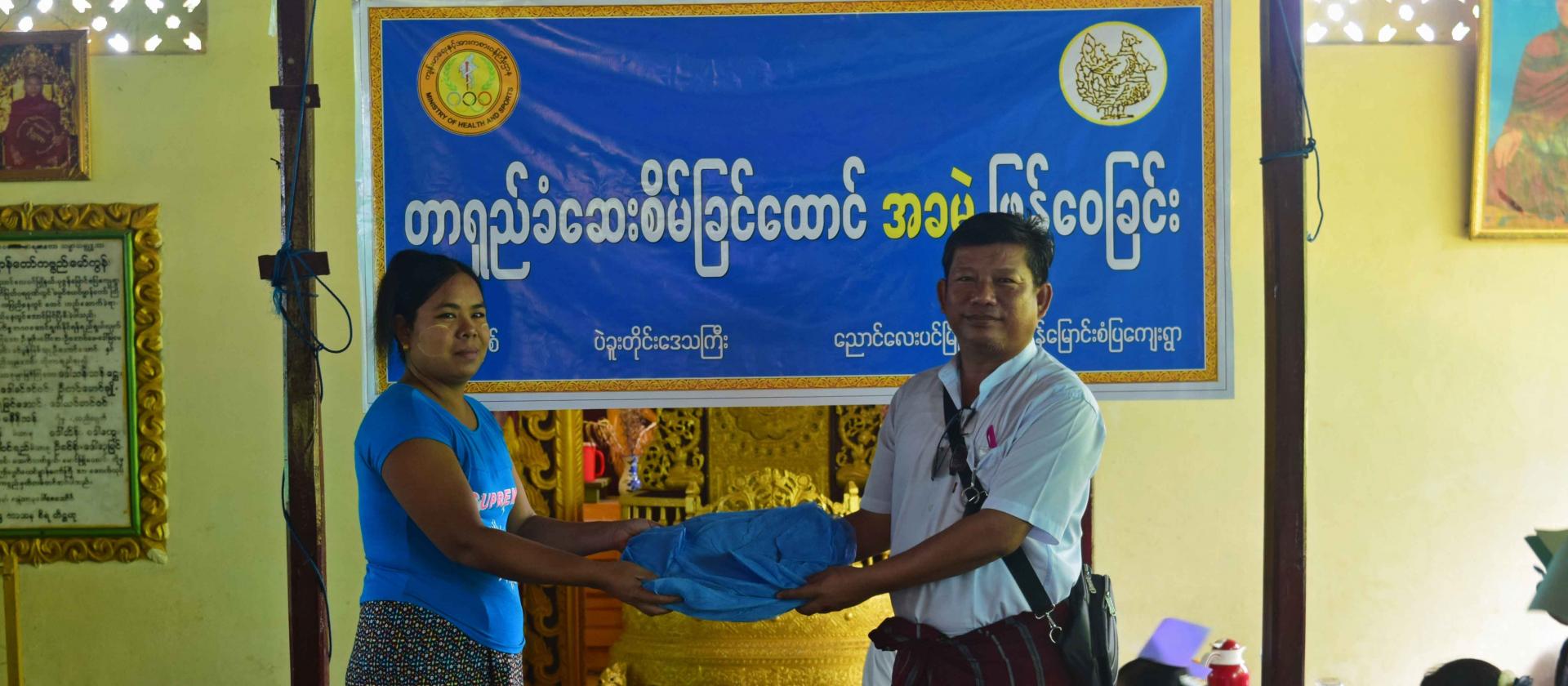 Dr Thaung Dan, Medical Superintendent of Nyaung Lay Pin Township, hands long-lasting insecticidal bed nets to a woman from Pazunmyaung village, Nyaung Lay Pin Township. Photo: UNOPS Dr Thaung Dan, Medical Superintendent of Nyaung Lay Pin Township, hands long-lasting insecticidal bed nets to a woman from Pazunmyaung village, Nyaung Lay Pin Township. Photo: UNOPS