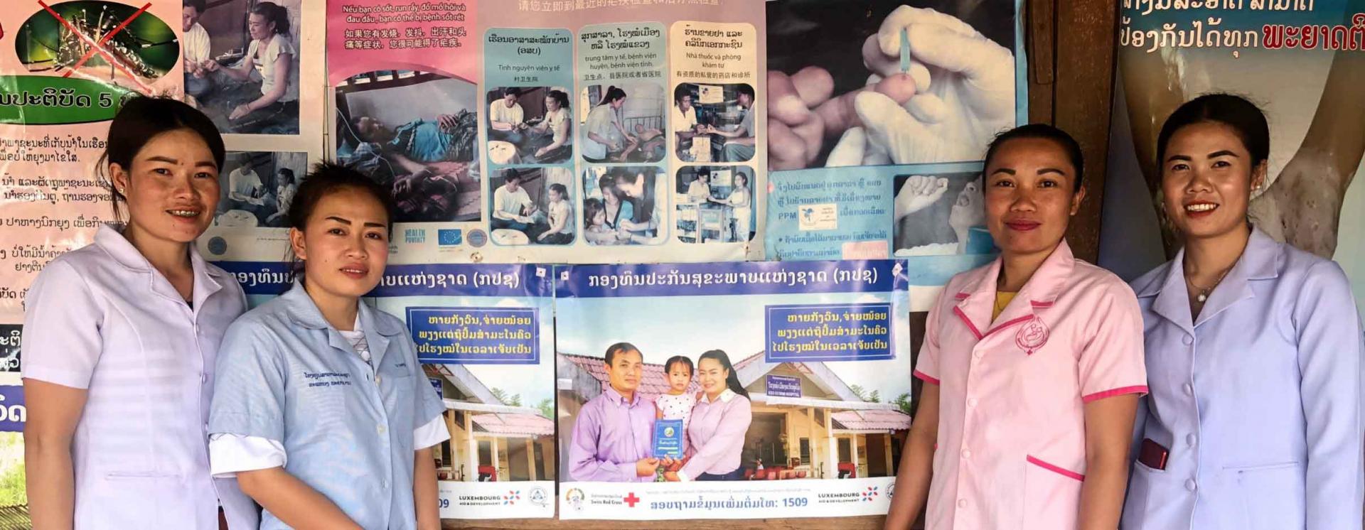 Nanoy Health Center team with health education posters displayed on a wall inside the center. Photo: Thipphaphorn Douangchak/UNOPS