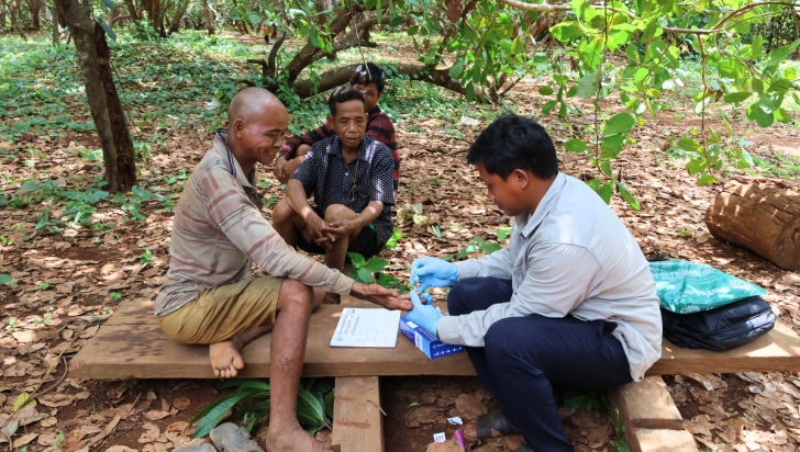 Mr. Meouy Buntear carries out a malaria test for workers who have just returned from the forest. Photo: Daneth Mao/ CRS
